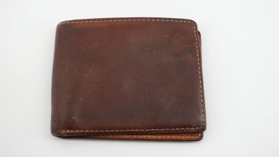 un portefeuille en cuir marron posé sur une surface blanche
