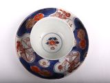 a blue and red bowl and saucer on a white table