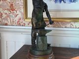 a bronze statue of a woman holding a hammer on a table