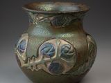 un vase vert orné de motifs bleus et verts