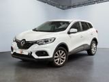 Une voiture blanche est garée dans une grande pièce au sol noir.