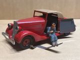 une petite voiture rouge avec un homme assis au volant