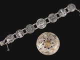 un gros plan d'un bracelet en argent et d'une pièce de monnaie sur fond noir