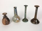 quatre vases de couleurs différentes posés les uns à côté des autres sur une surface blanche