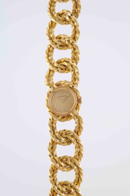 a close up of a gold bracelet with a coin on it