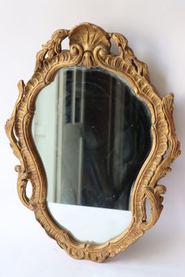 un miroir doré accroché au mur, à côté d'un mur blanc