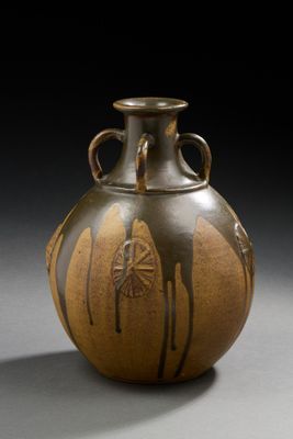 un vase marron posé sur une table sur fond noir