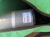a green bag with a bottle of water inside of it