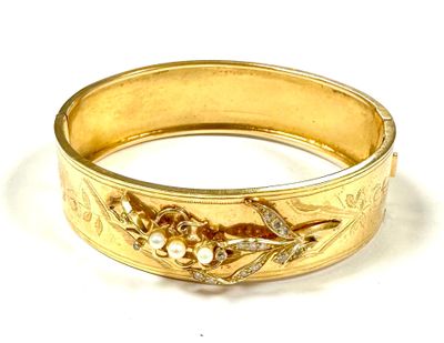gold bangle with flowers and pearls on it on a white surface