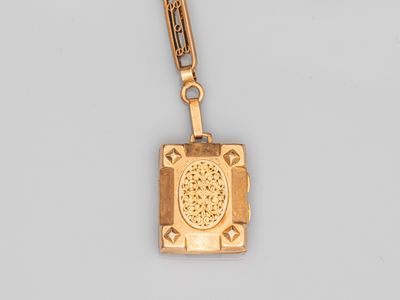 un gros plan d'un collier en or avec un livre suspendu à une chaîne