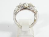 a close up of a ring with pearls and diamonds on a stand
