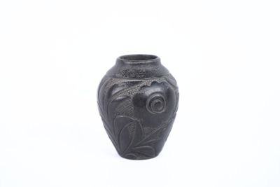 a black vase with a bird on it on a white surface
