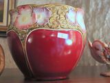 a red vase sitting on top of a table next to a golden egg