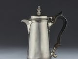 an antique silver coffee pot with a handle on a white surface