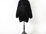 un manteau de fourrure noir posé sur un mannequin, sur fond blanc