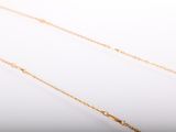 a close up of a gold necklace with a diamond on a white background