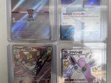 four pokemon cards in a plastic case on a table