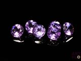 un groupe de pierres précieuses violettes posées sur une surface noire