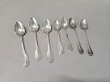 six silver spoons are lined up in a row on a table
