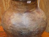 un grand vase posé sur une table en bois, sur laquelle est accrochée une étiquette