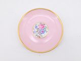 pink plate with gold rim with a floral design on it