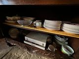 many plates and bowls sitting on a shelf in a room