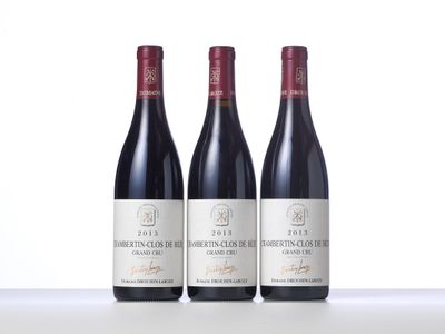 three bottles of red wine are lined up on a table