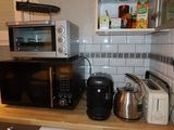 a kitchen with a microwave, toaster, toaster, kettle, and toaster oven
