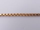 a close up of a gold bracelet on a white surface