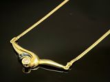 un collier en or orné d'un diamant, posé sur un fond noir