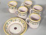 several cups and saucers sitting on a table with a bowl and plate