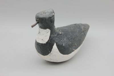 un petit canard noir et blanc posé sur une surface blanche