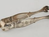 an antique silver plated fish shaped object on a white surface