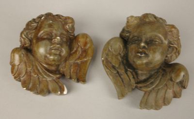 deux statues d'anges posées sur une surface blanche, avec un fond blanc