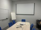 une photo d'une salle de conférence avec un écran de projection et des chaises bleues