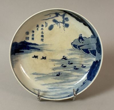 a blue and white plate with a picture of a man on a boat