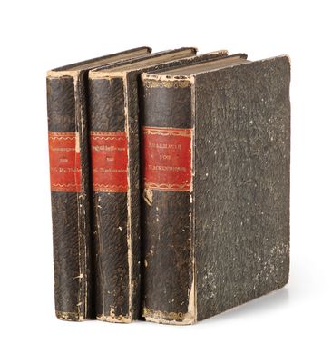 three old books sitting on top of each other on a white surface