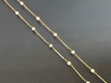 a close up of a gold chain with pearls on it