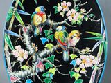 a black plate with birds and flowers on it
