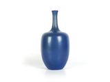 un vase bleu posé sur une surface blanche