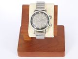 une montre en argent posée sur un socle en bois, sur fond blanc