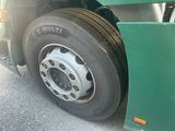 a green semi truck with a flat tire parked on the side of the road