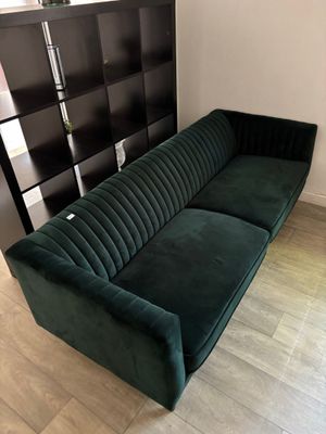 un canapé vert dans un salon avec une bibliothèque