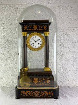 une petite horloge sous un dôme de verre sur une table