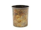 une tasse en métal posée sur une surface blanche