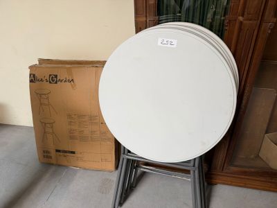 une table ronde blanche avec un piètement en métal et une boîte en carton à l'arrière-plan