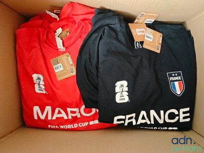 trois t-shirts dans une boîte en carton sur laquelle sont apposées des étiquettes