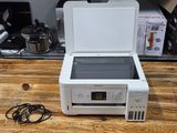 a white printer sitting on a wooden table next to a coffee pot