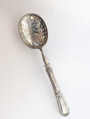 une cuillère en argent avec un manche sur une surface blanche