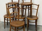quatre chaises en bois sont empilées les unes sur les autres devant un mur